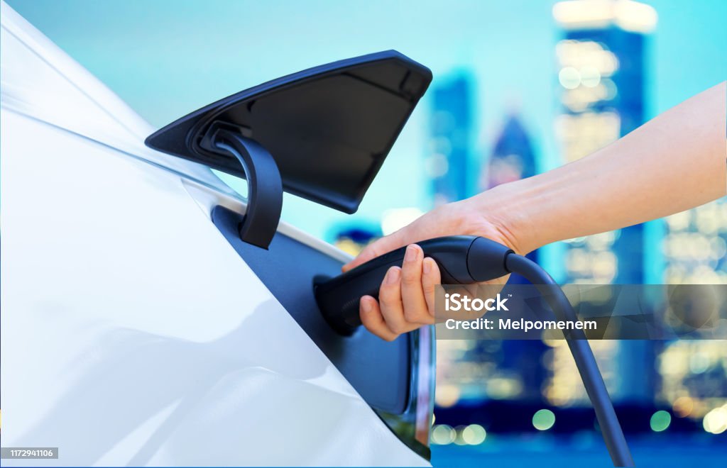 Person charging an electric vehicle Person charging an electric vehicle in the city High Angle View Stock Photo