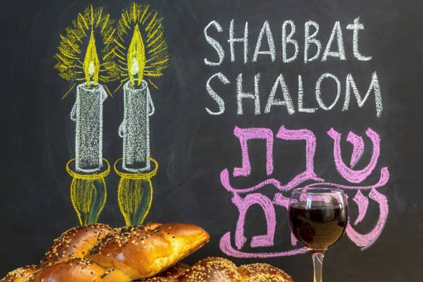 Jewish greetings Shabbat Shalom and candles painted on a chalkboard. May you dwell in completeness on this seventh day. Challah and glass of wine. stock photo