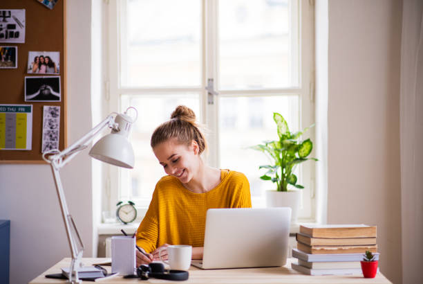 una giovane studentessa seduta al tavolo, che studia. - furniture internet adult blond hair foto e immagini stock