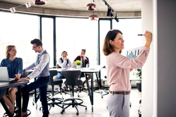 istock Businesspeople working in an office, writing on whiteboard. 1172944195