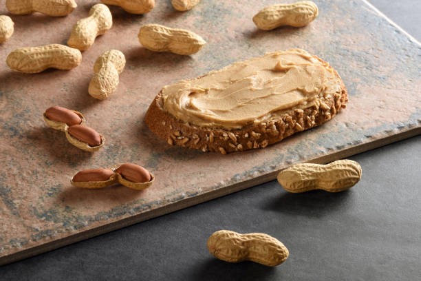 istock Peanut butter on a bread slice with shelled peanuts, still life 1172950557