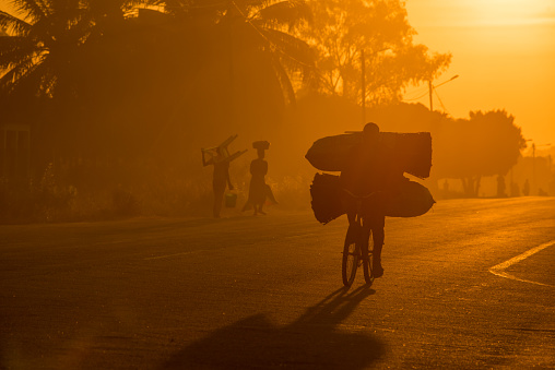 Hombre en una bicicleta con bolsas al amanecer photo