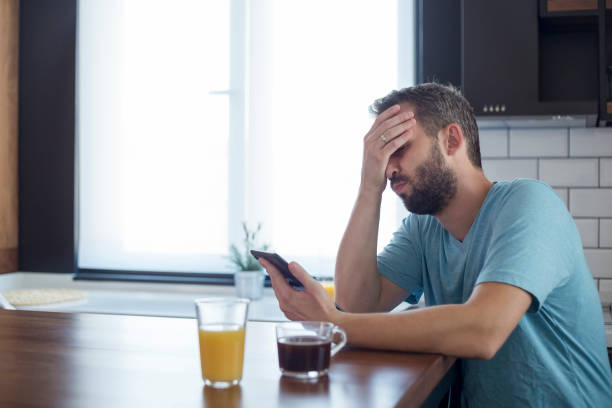 istock Young man disappointed while working on tablet. He is sitting at his kitchen table at home. 1172956340