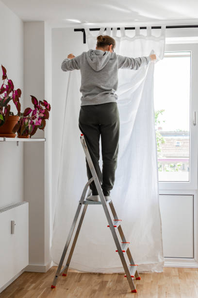 istock Woman hangs white curtains on the curtain rod 1172959520
