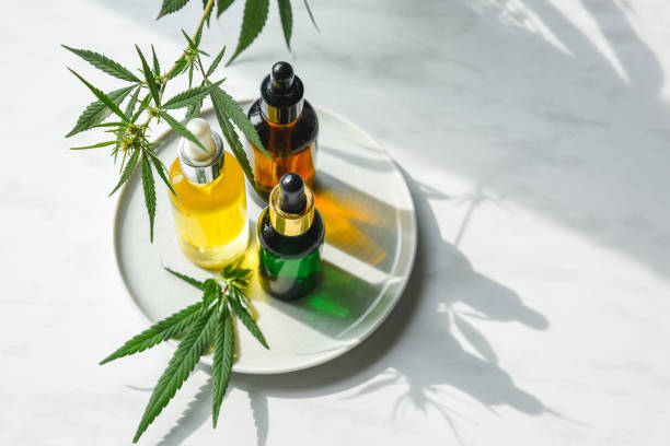 glazen flessen met cbd olie, thc tinctuur en hennep bladeren op een marmeren achtergrond. platte lay cosmetica cannabisolie. - druppelfles stockfoto's en -beelden