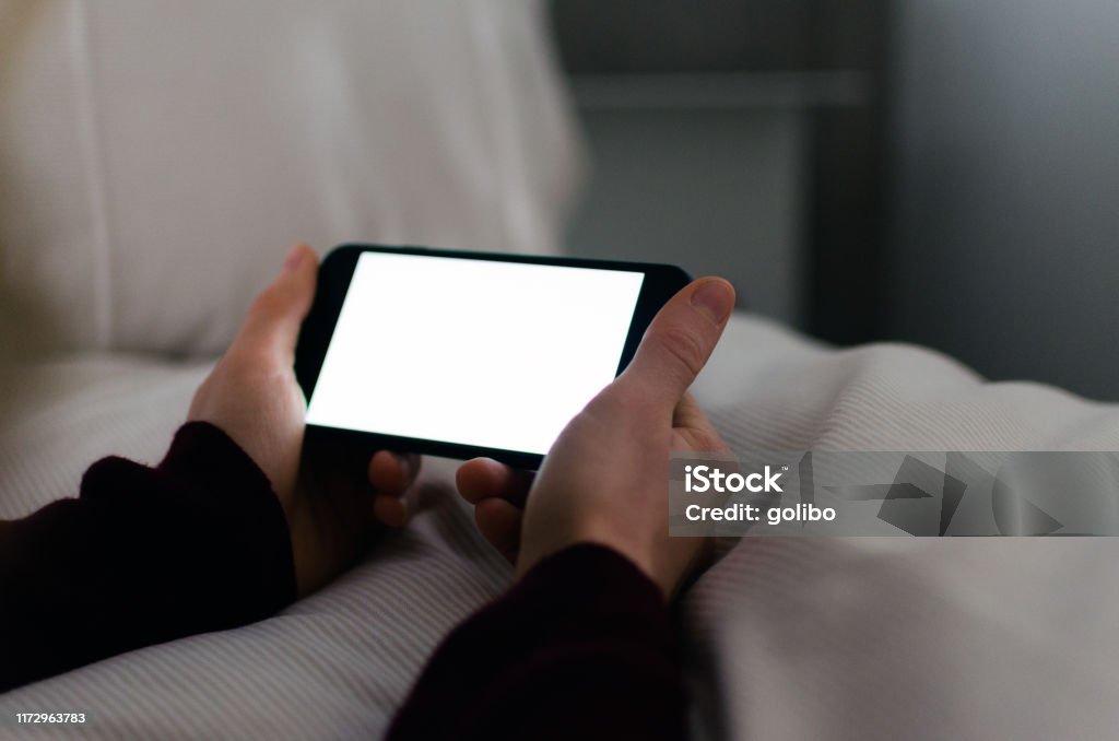 Lit smartphone with blank screen and copy space Woman holding a modern smart phone with touch screen and she is looking at a white screen with a blank display and copy space Telephone Stock Photo Lit smartphone with blank screen and copy space Woman holding a modern smart phone with touch screen and she is looking at a white screen with a blank display and copy space Telephone Stock Photo