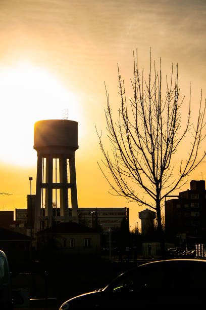 istock Sunset with the orange sky, a water tank and a tree without leaves backlit 1172963862