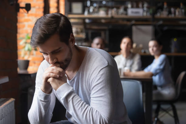 istock Sad guy sitting alone separately from other mates in cafe 1172964140