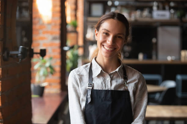 Happy mixed race female in apron smiling looking at camera Head shot portrait successful mixed race businesswoman happy restaurant or cafeteria owner looking at camera, woman wearing apron smiling welcoming guests having prosperous catering business concept television host stock pictures, royalty-free photos & images