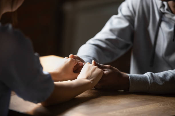 istock Close up hands diverse couple sitting at table holding hands 1172964190