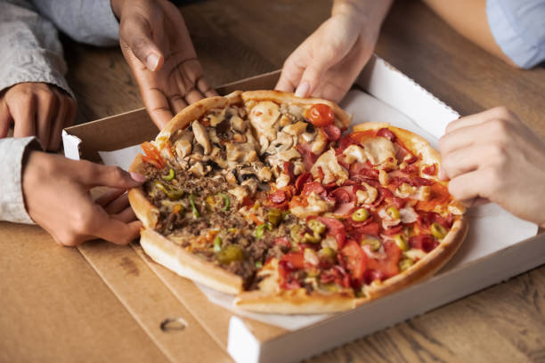 ピザのスライスを共有する多民族の空腹の人々は、手をクローズアップ - pizza pizzeria friendship people ストックフォトと画像