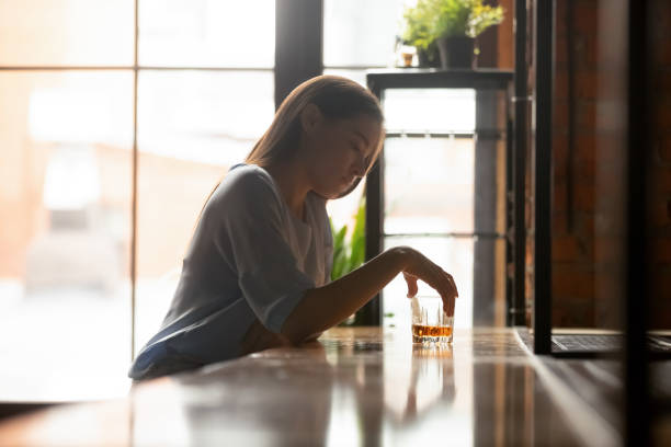 アルコール飲料を飲んでバーカウンターに座っている若い悲しい女性 - alcoholism assistance photography people ストックフォトと画像