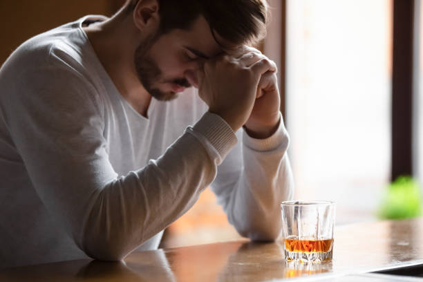 l'uomo seduto sul bancone del bar si sente depresso bevendo bevanda alcolica - alcoholism assistance photography people foto e immagini stock