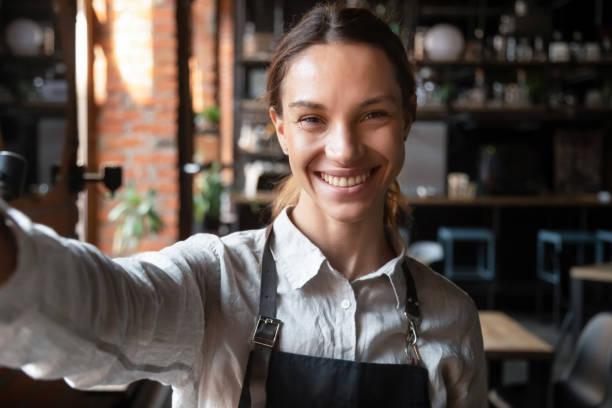 istock Mixed race female in apron smiling looking at web camera 1172964319