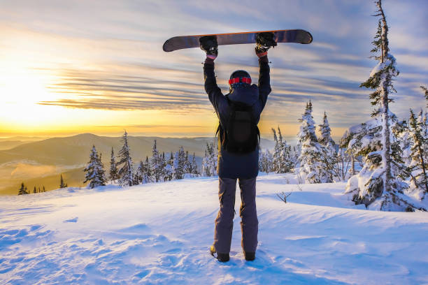 istock Successful young man snowboarding in the mountains Sheregesh, resting on mountain top. Caucasian Snowboarder on a background of a bright sunset. Winner on the top of the mountain. Taste of victory. 1172965683