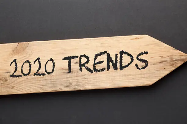 The text 2020 Trends written on old wooden arrow on black background.