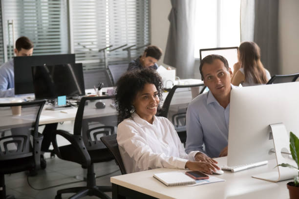 istock Diverse colleagues collaborating at pc in coworking office space 1172966484