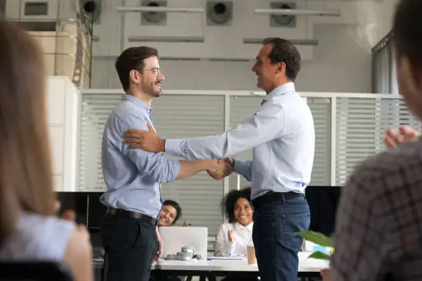 Boss or CEO shake hand of male employee congratulating with job promotion at work, company employer handshake newcomer or newbie greeting with employment or hiring. Recruitment concept