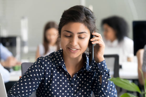 istock Smiling female employee talk over phone at shared workplace 1172966602