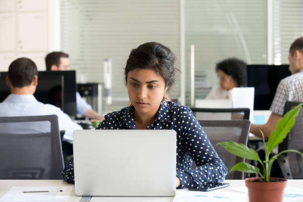 istock Focused female intern busy working on laptop in office 1172966604