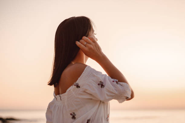 istock beautiful young brunete woman's hair develop in the wind on the beach. the model wearing boho style clothes, girl enjoys freedoom and sunrise 1172966755