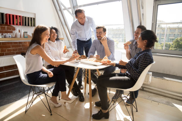 istock Happy employees eating pizza having fun in office together 1172966796