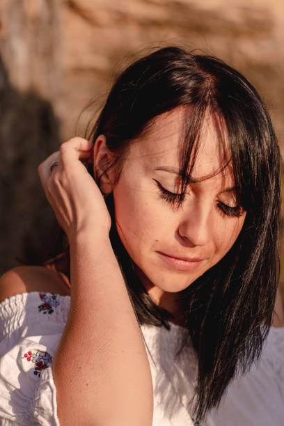 istock beautiful young brunete woman's hair develop in the wind on the beach. the model wearing boho style clothes, girl enjoys freedoom and sunrise 1172967583