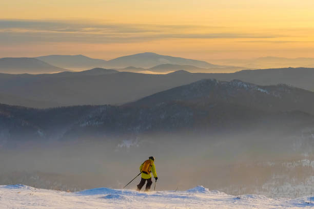 giovane di successo che scia sulle montagne sheregesh. sciatore appoggiato sulla cima della montagna. sciatore caucasico su uno sfondo di cielo. sciatore su uno sfondo di un tramonto luminoso. arcobaleno in montagna. - sheregesh foto e immagini stock