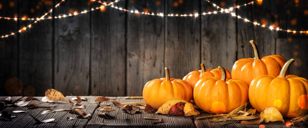 istock Pumpkins And Leaves On Rustic Wooden Table With Lights And Bokeh 1172969767