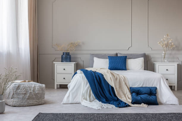 istock Blue pillow and blanket on white bed in spacious bedroom interior, copy space on empty grey wall 1172970018