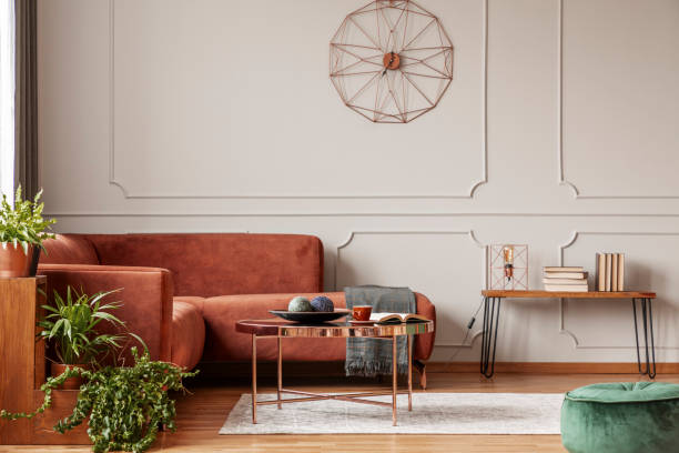 istock Brown comfortable corner sofa in elegant living room interior with grey wall with molding and fancy clock 1172971034