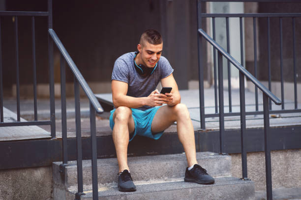 istock Young man resting after jogging and using smartphone 1172971947