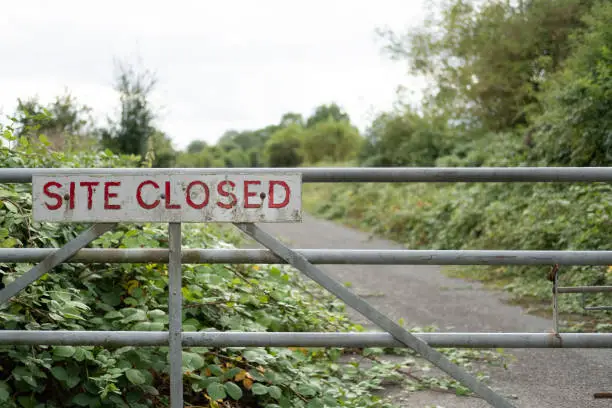 Vegetation is starting to take hold of the access road beyond the gate.