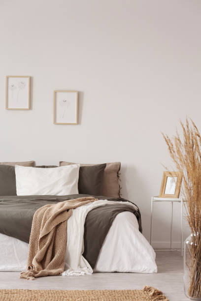 istock Graphics in wooden frames on white empty copy space wall in bedroom with comfortable bed with black and grey pillows and duvet 1172972428