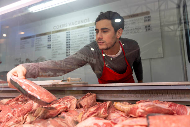 istock Young butcher grabbing a piece of meat from fridge 1172976340