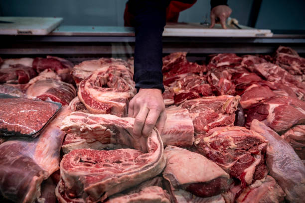 varietà di carne fresca presso la macelleria e uomo irriconoscibile afferrando un pezzo - butchers shop meat market pork foto e immagini stock