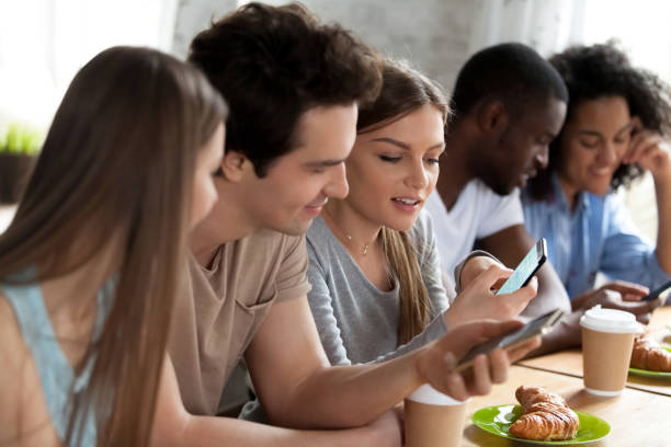 istock Mixed race happy friends using mobile phones in cafe. 1172977578