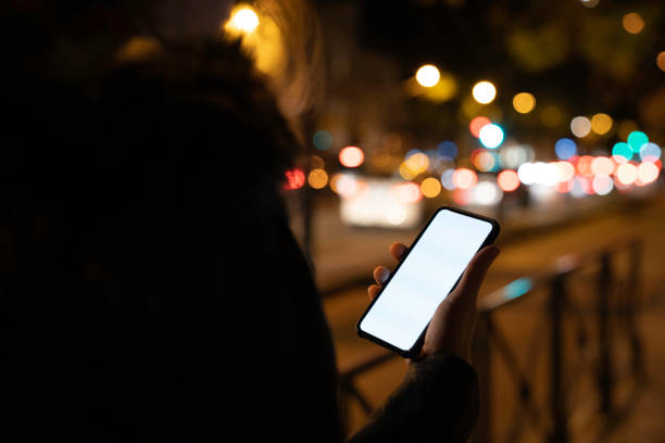 istock Woman holding blank phone with white screen and copy space by night 1172979232