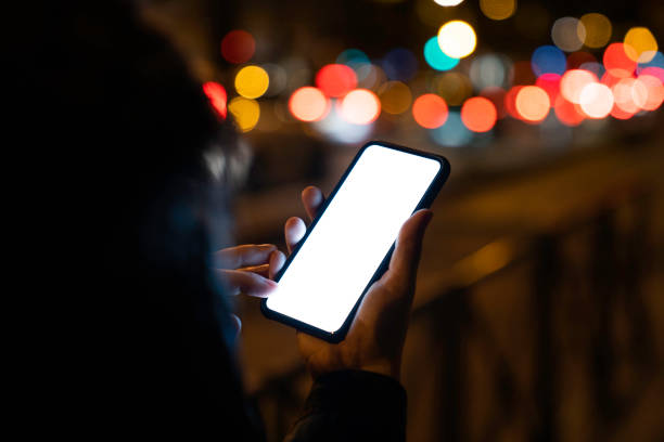 istock Woman holding blank phone with copy space and white screen by night 1172979320