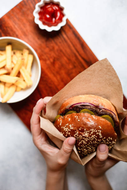 istock Woman's hands holding juicy bun burger with meat. 1172985517
