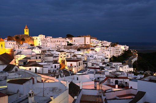 The photo was taken looking at the town by night. The houses are lit by street lights and light and the sky is dark blue. There is copy space for text.