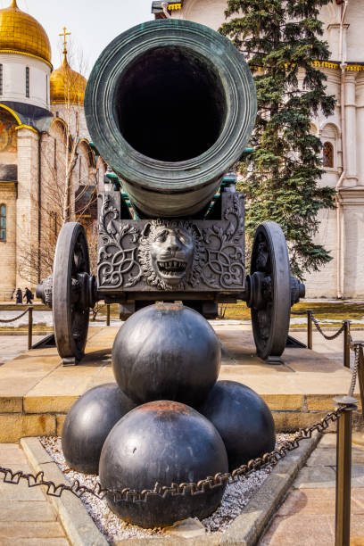 Huge old tarnished ornate canon, Tsar Pushka, on wheels with stack of cannonballs in front, located inside of Kremlin walls, Red Square Moscow Russia