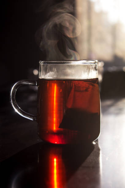 istock Vapor rises from a glass cup of tea with teabag inside. 1173006211
