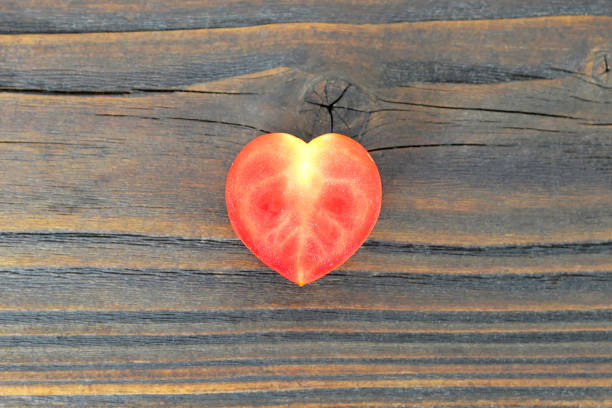 Fresh organically grown German Johnson heirloom tomato on a rustic white painted wooden background