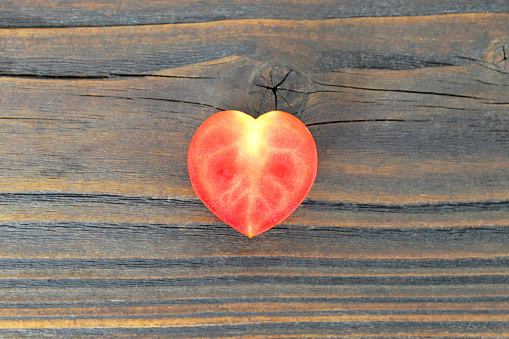 Heart shaped tomato on wooden background