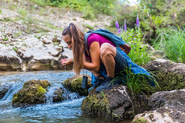 istock Young woman Drinking water from river 1173006429