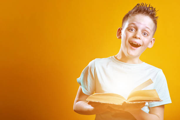 istock cheerful boy in a light t-shirt holding a book on a colored background 1173009771