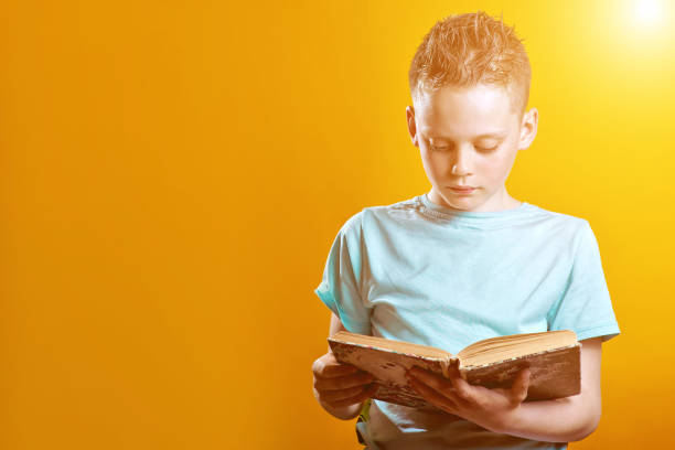 istock cheerful boy in a light t-shirt holding a book on a colored background 1173009778