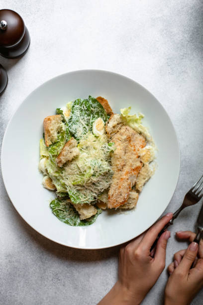 Top view of Female hands eating caesar salad.