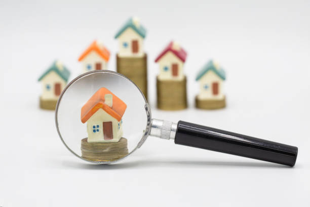 istock House searching concept with a magnifying glass on white background. Stack coin and bar graph with grow,   magnifying glass searching for a new home, Loan for real estate. 1173021605